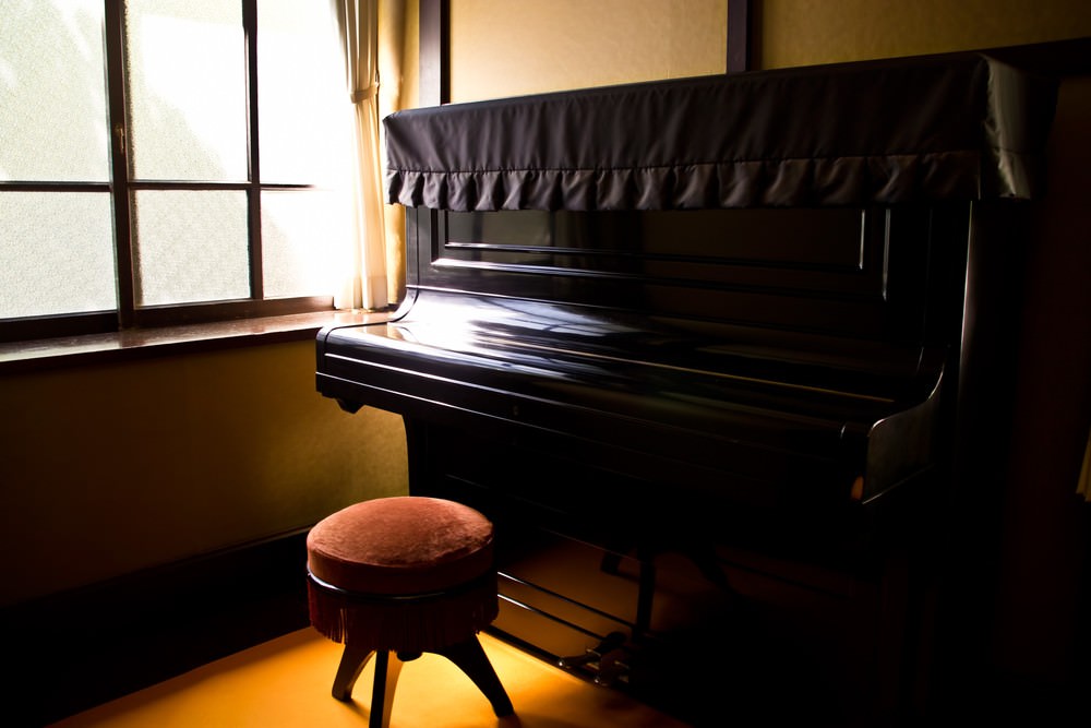 窓際の古いピアノの写真素材