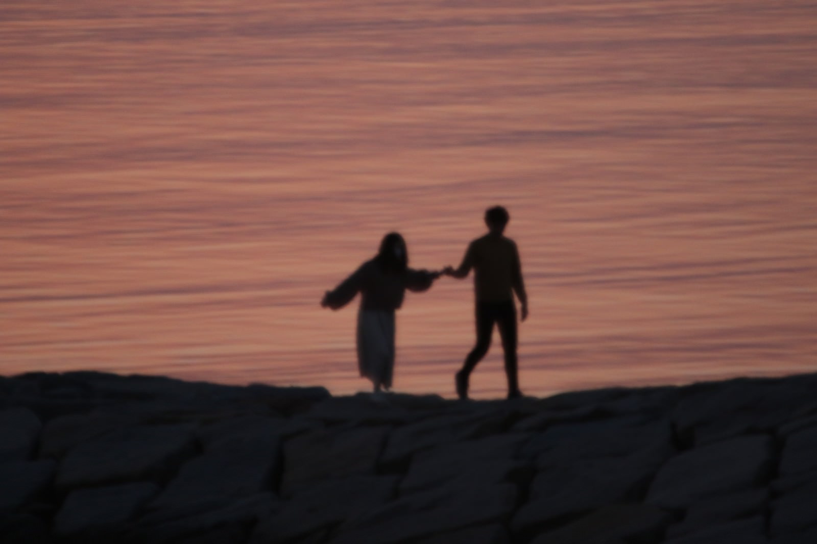 海岸で手を取るカップルのシルエットの写真素材 ぱくたそ