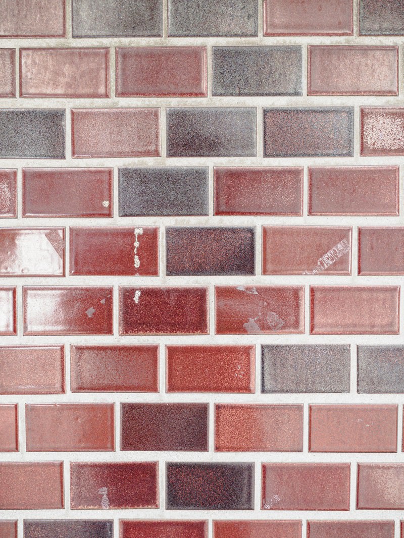 「テカるレンガ風のタイル壁 | フリー素材のぱくたそ」の写真