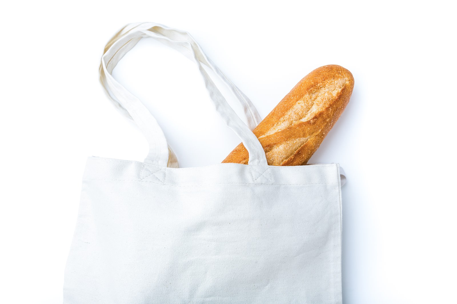 「無地のトートバッグに入ったフランスパン | フリー素材のぱくたそ」の写真
