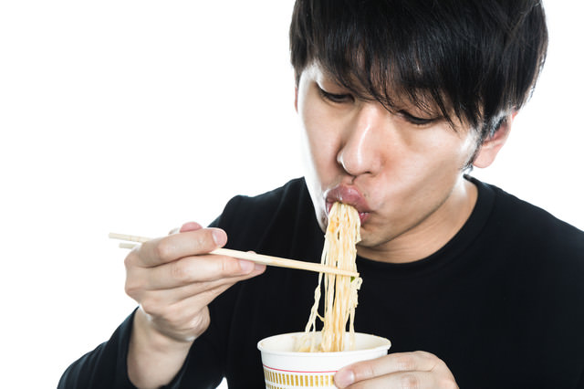 カップラーメンをすする男性