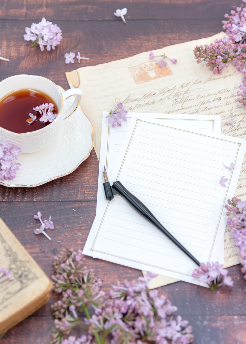 「ティーカップに浮かぶ花弁と白紙の手紙」の写真