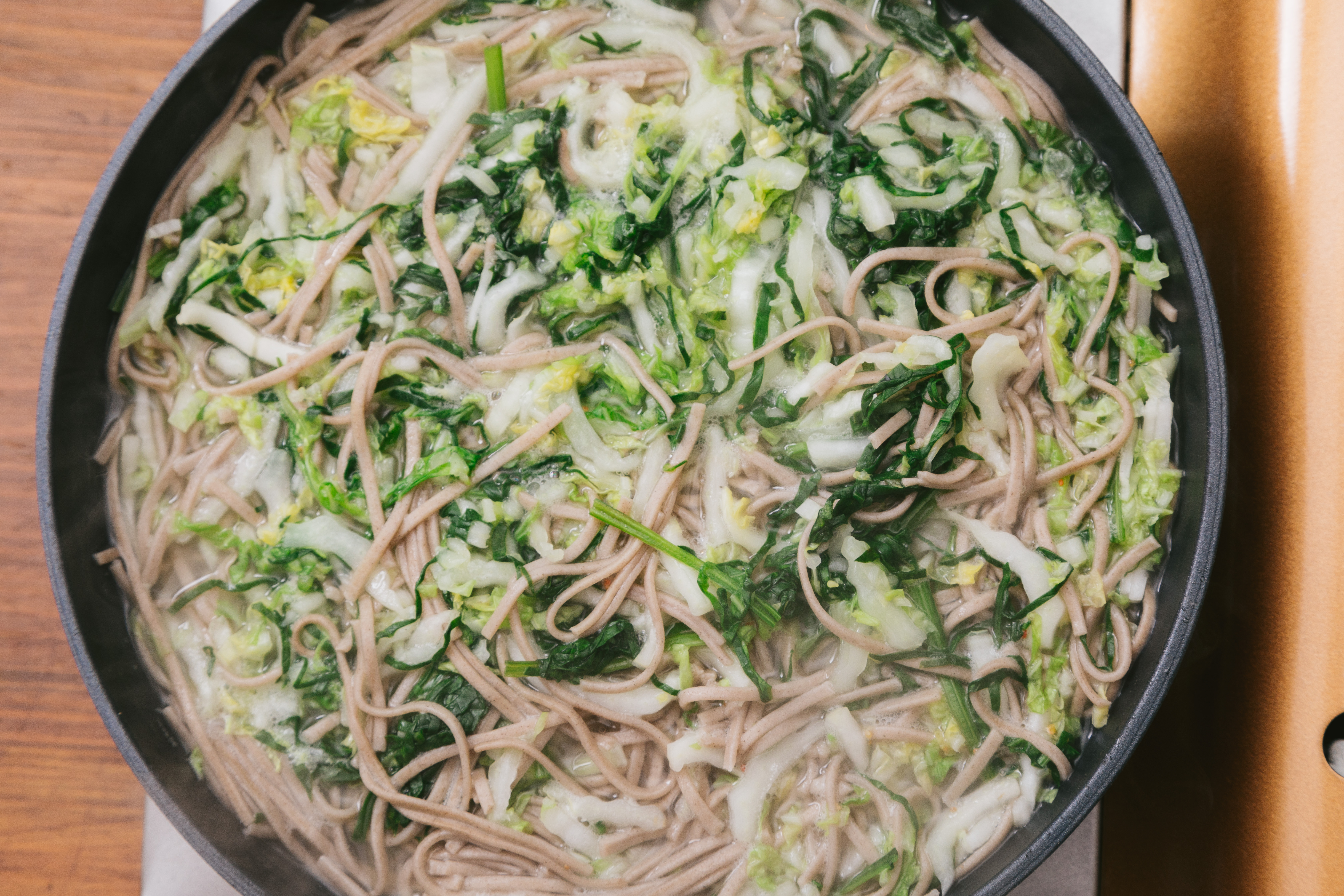 鍋にお湯を沸かしてそばと大根 白菜 ほうれん草を加えるの写真素材 ぱくたそ
