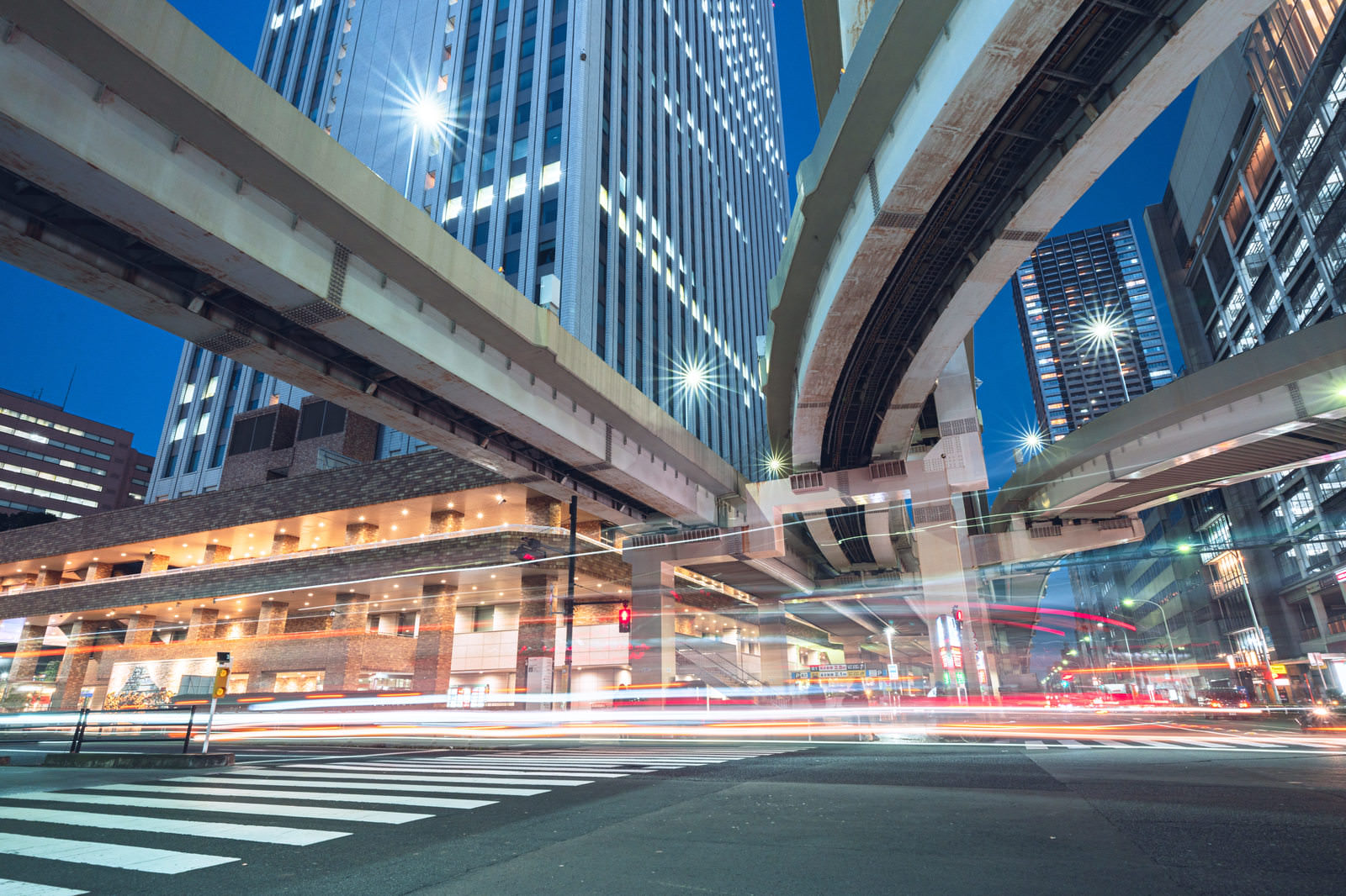 「首都高下の交差点の光跡 | フリー素材のぱくたそ」の写真