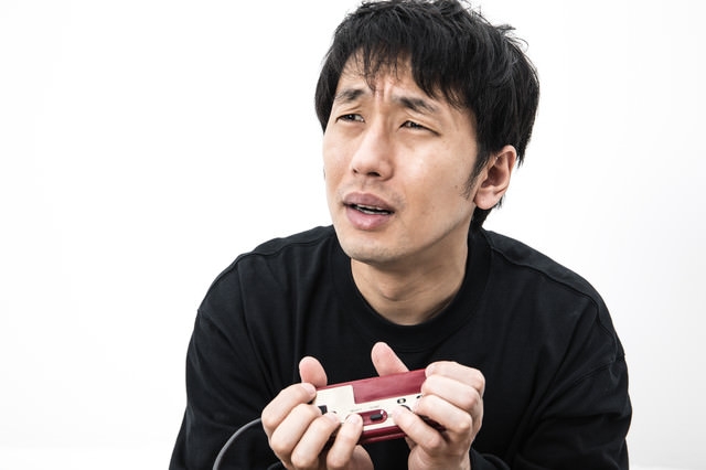 こんなコントローラーの持ち方じゃうまくプレイできないと涙目のゲーマーの写真