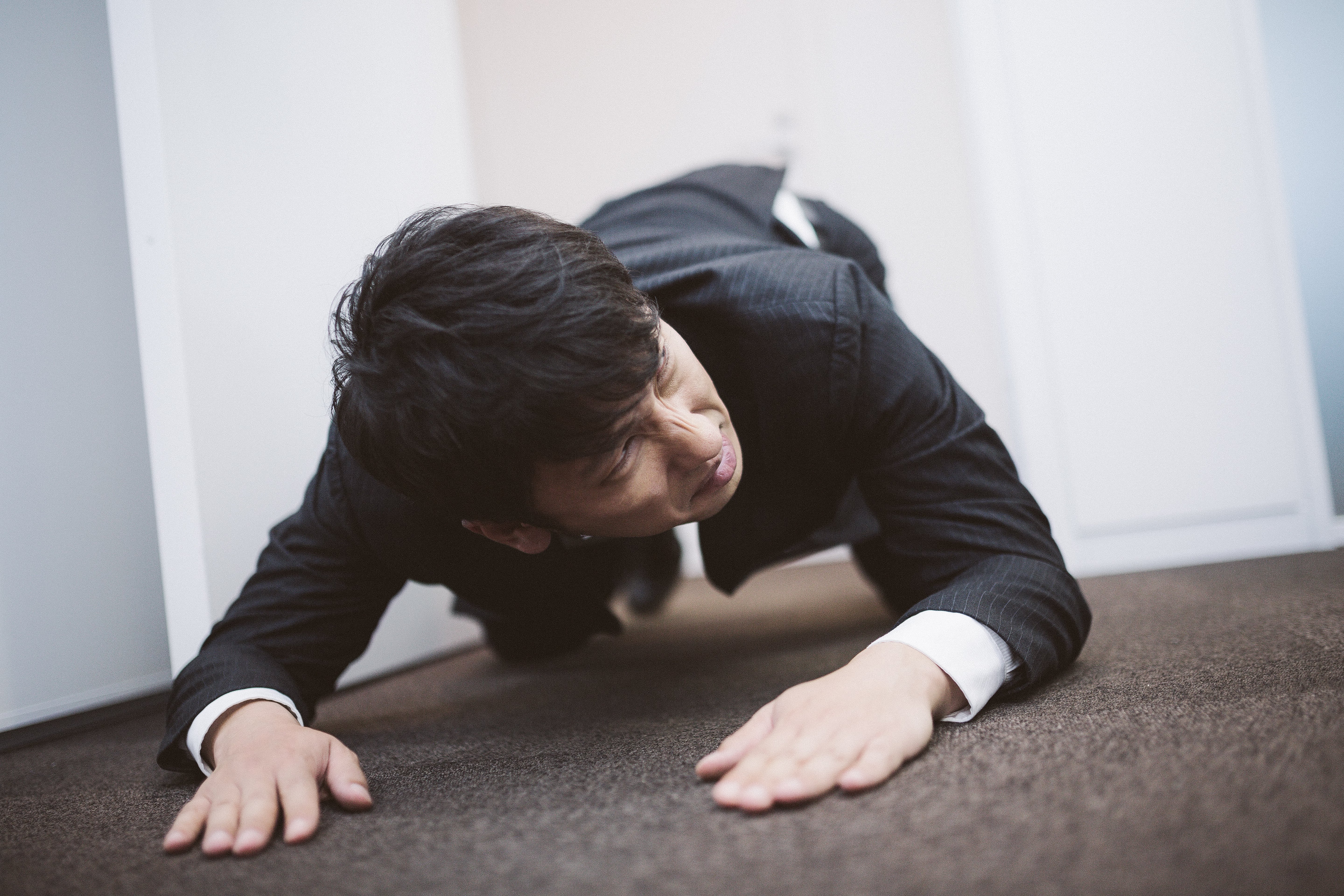 土下座をしながら次の予定に遅れないよう時計を気にするビジネスパーソンの写真を無料ダウンロード フリー素材 ぱくたそ