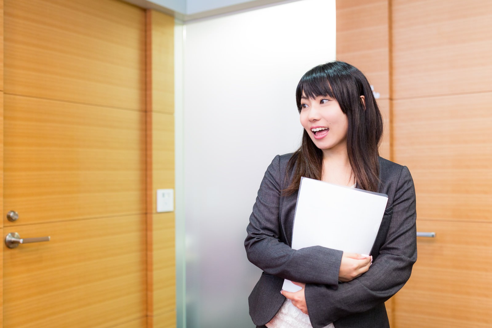 「おはようございます〜！」と明るい笑顔で挨拶をする女性社員の写真（画像）を無料ダウンロード フリー素材のぱくたそ