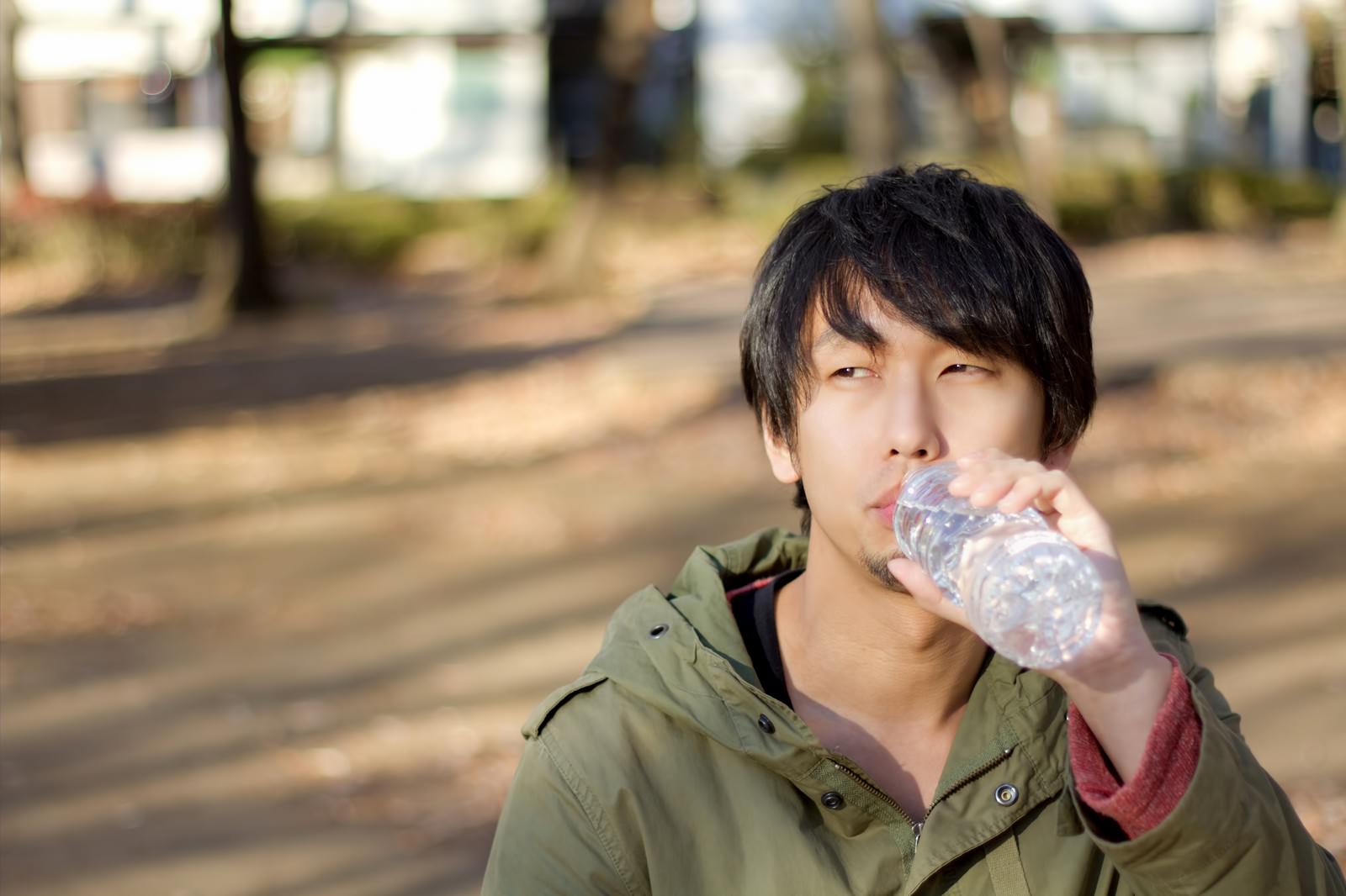 寂しく公園でペッドボトルの水を飲む男性の写真を無料ダウンロード フリー素材 ぱくたそ