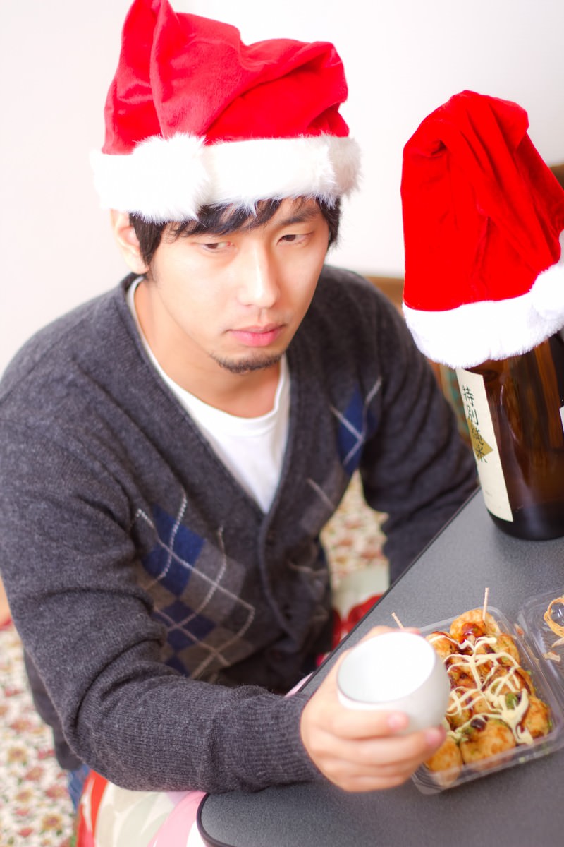 「孤独なクリスマスでもお酒とおつまみがあれば負けない！表情の男性 | フリー素材のぱくたそ」の写真［モデル：大川竜弥］