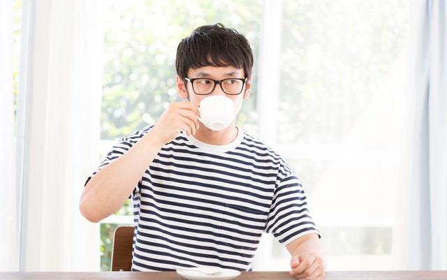 リビングで深煎りコーヒーを飲む男性