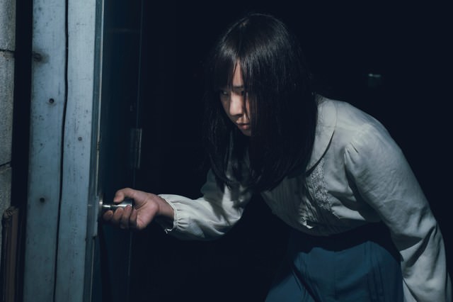 「恐る恐る扉を開ける女性」のフリー写真素材