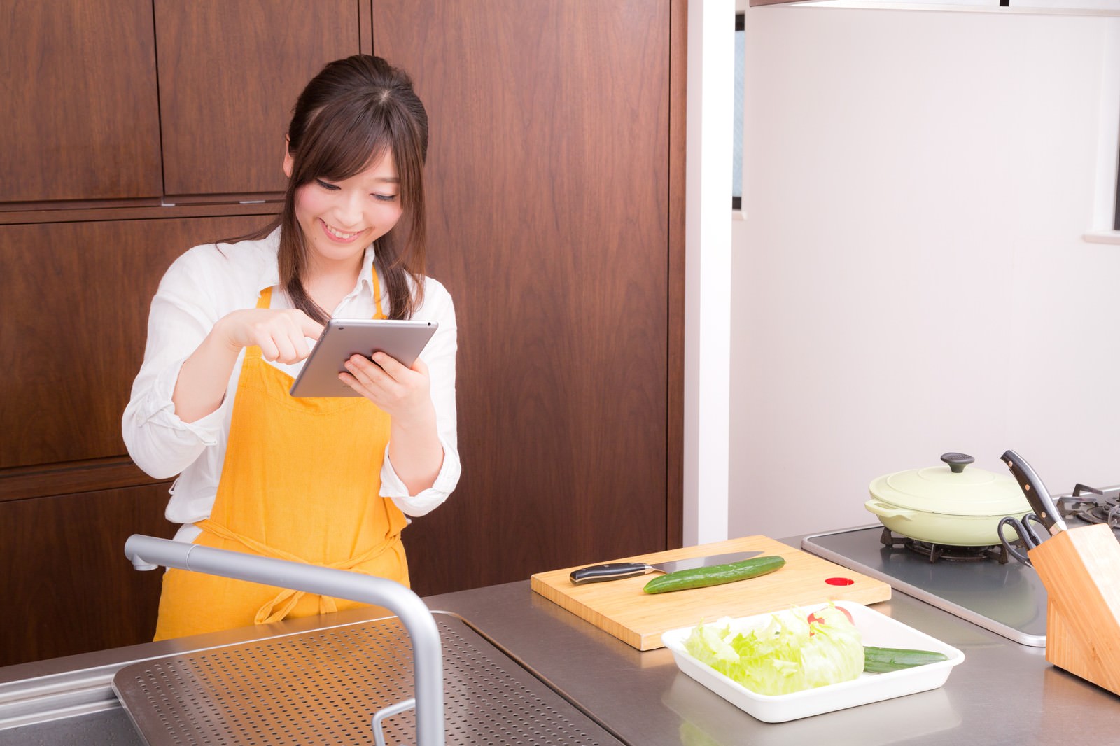 「料理をはじめる前に、タブレットでレシピを確認する嫁」の写真［モデル：五十嵐夫妻］