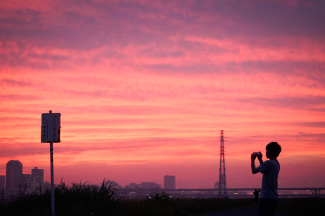 夕焼け空を撮影する少年