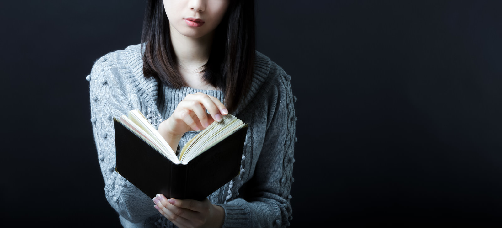 「暗闇でページをめくる女性」の写真