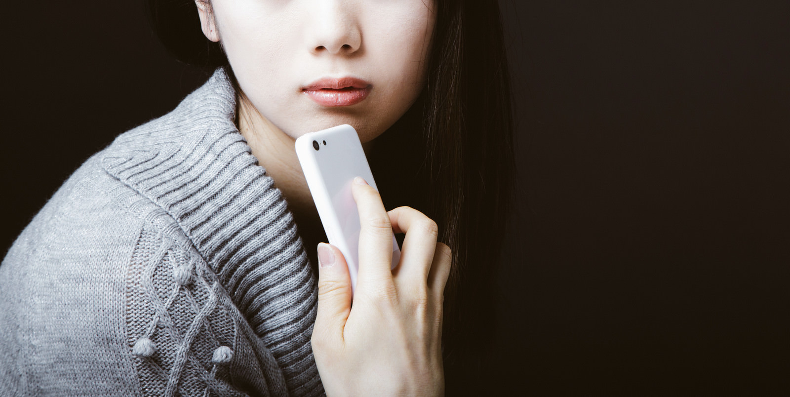 「スマホを顎にあてて憂鬱な女性」の写真