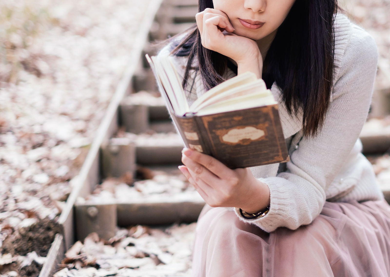 「屋外で洋書を読む女性」の写真