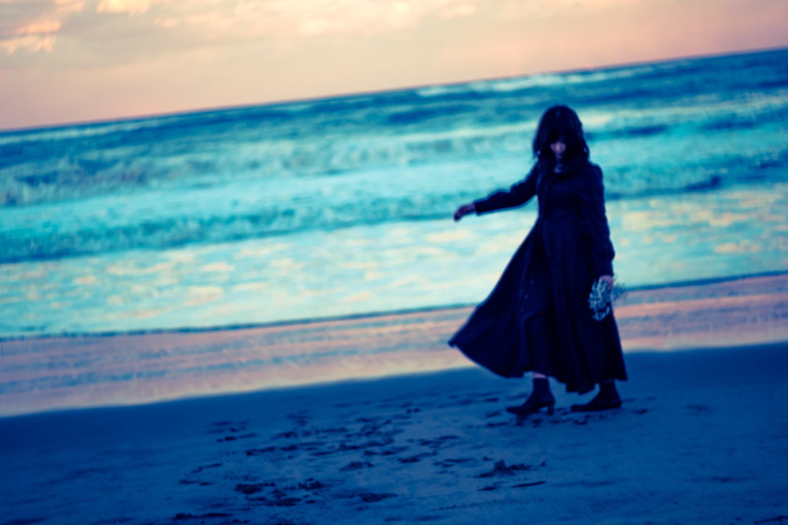 「浜辺を彷徨う黒服の女性 | フリー素材のぱくたそ」の写真