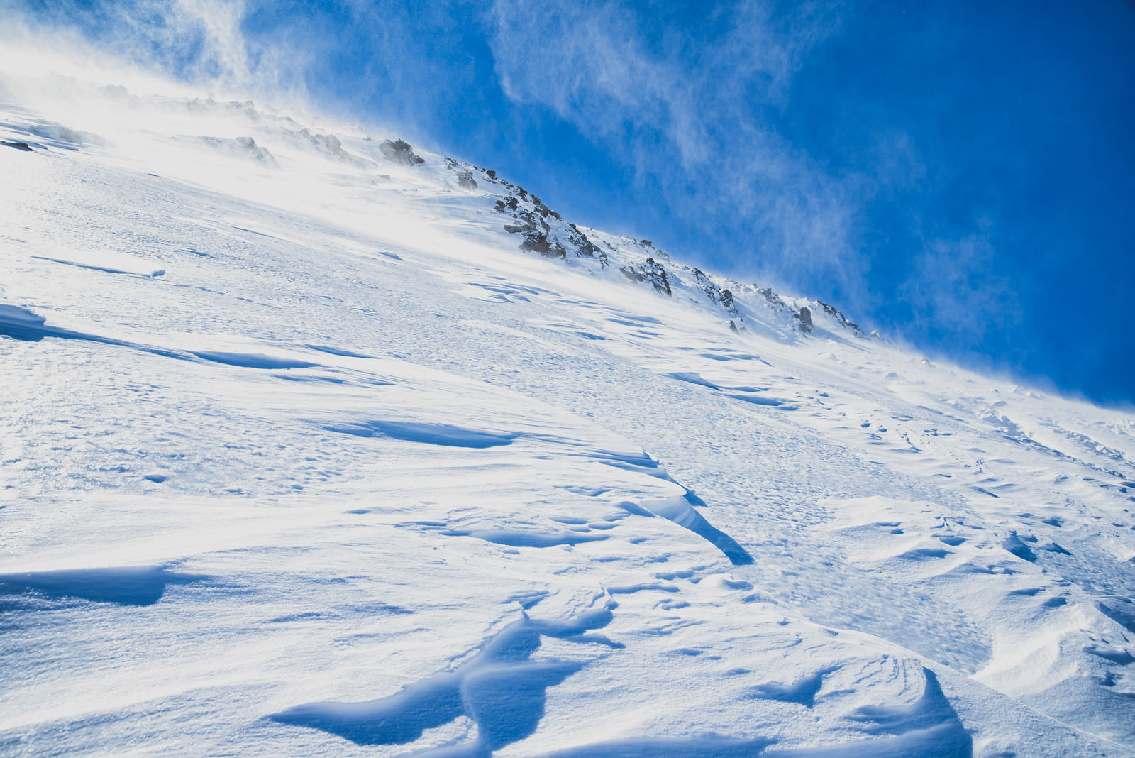 風吹き荒れる雪山の斜面の写真を無料ダウンロード フリー素材 ぱくたそ