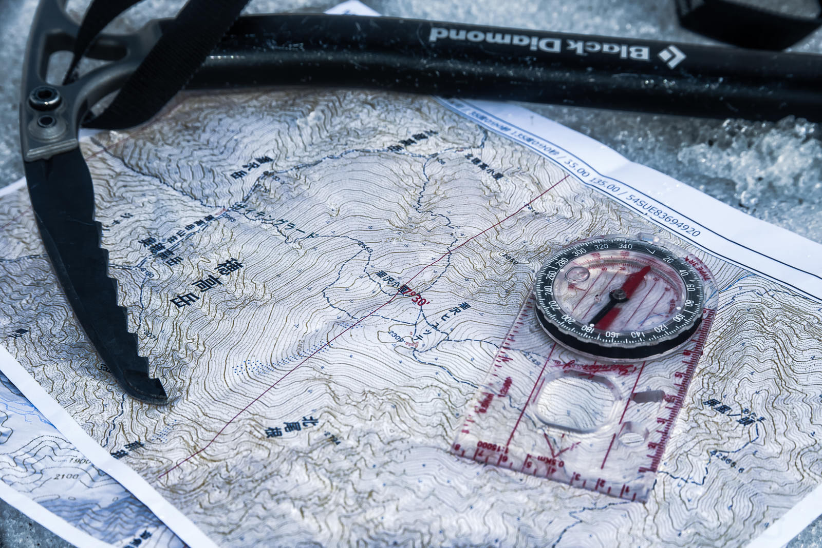 「登山の装備（地図とコンパスとピッケル）」の写真