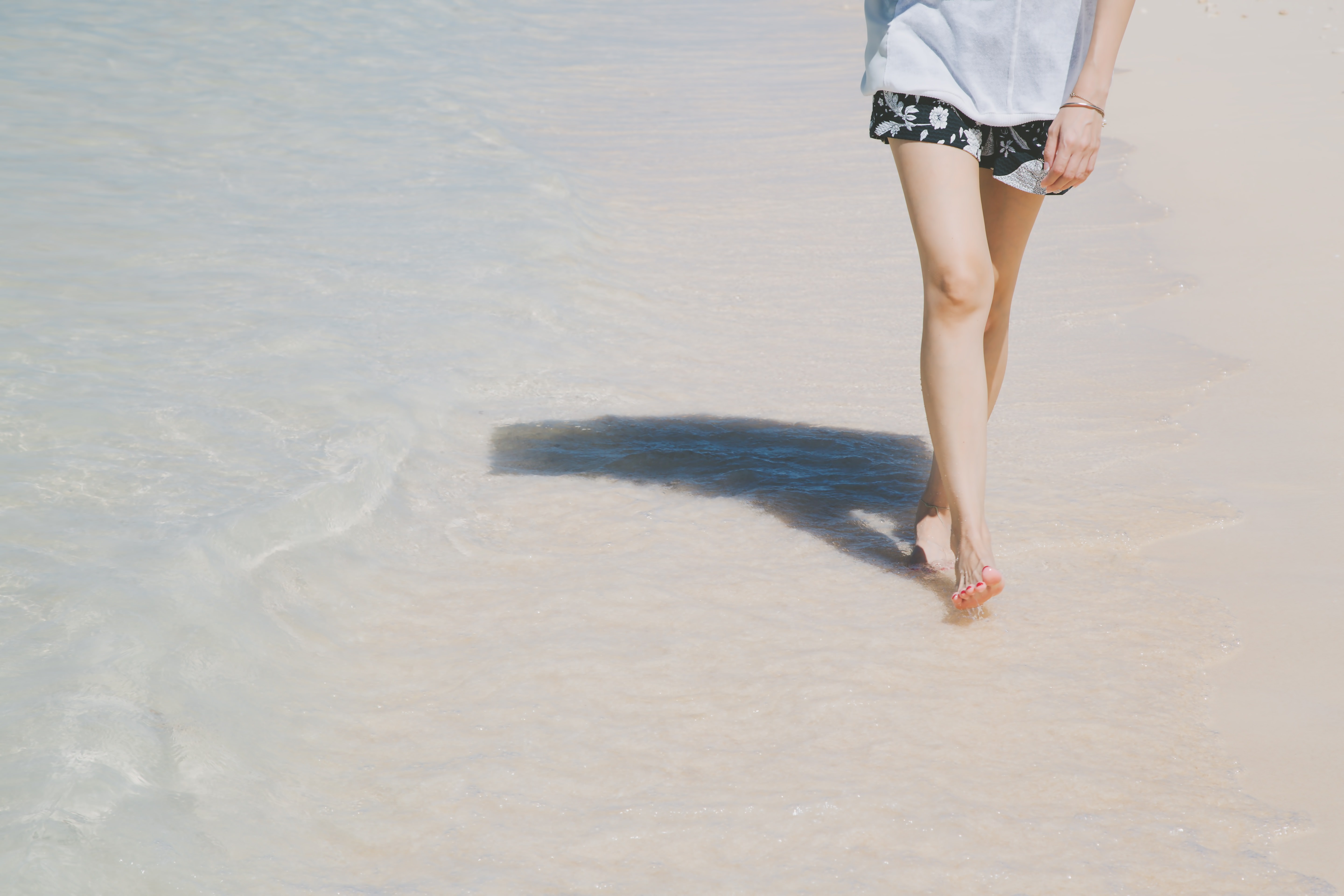 日傘をさして砂浜を歩く女性の足元の写真素材 ぱくたそ