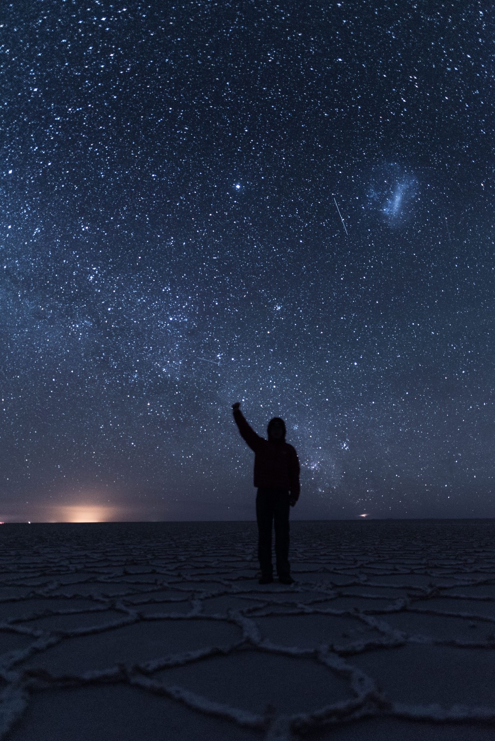 ウユニ塩湖の星空の下で手をあげる観光客のフリー素材 ぱくたそ