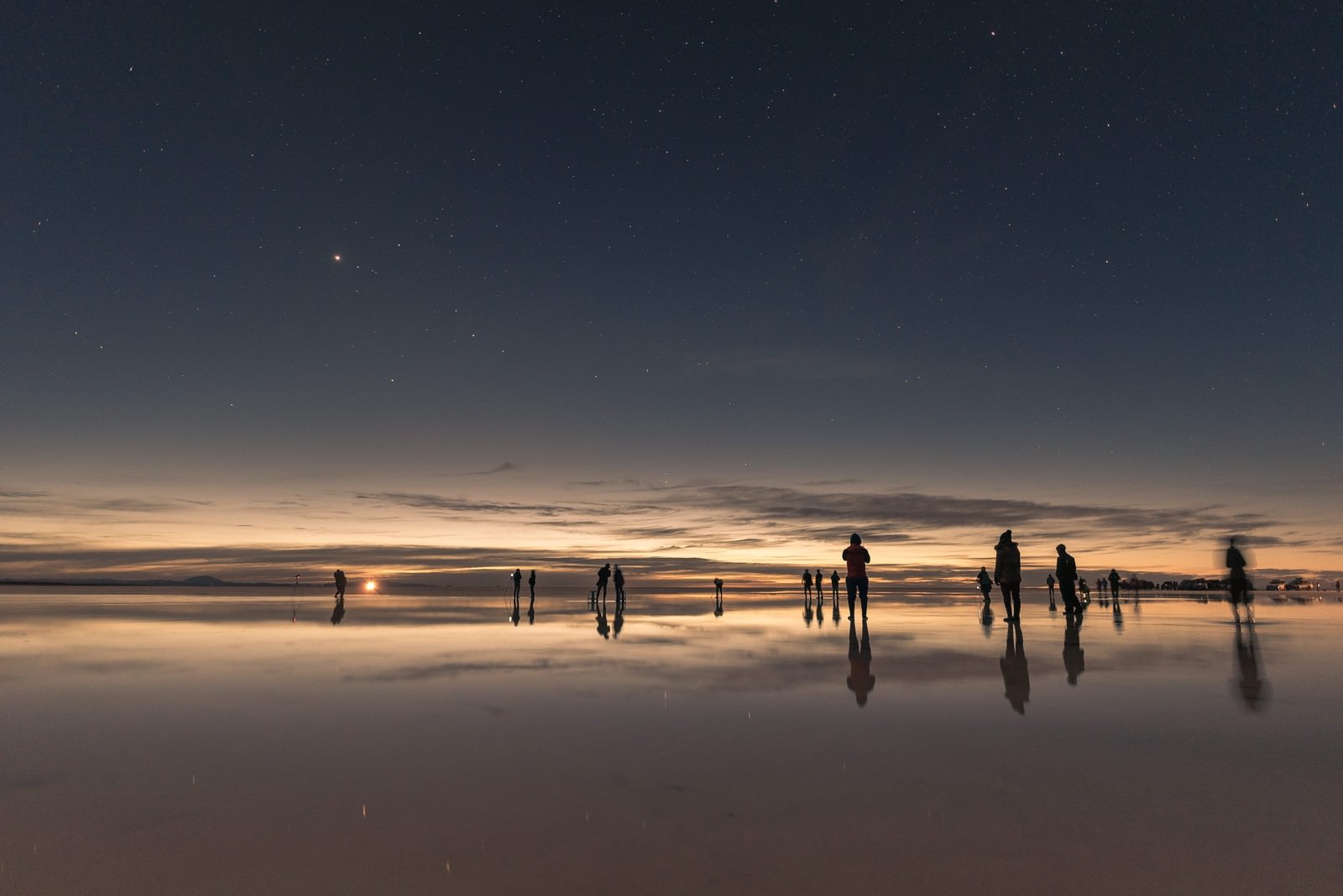 「ウユニ塩湖の日没と星空を楽しむ観光客 | フリー素材のぱくたそ」の写真