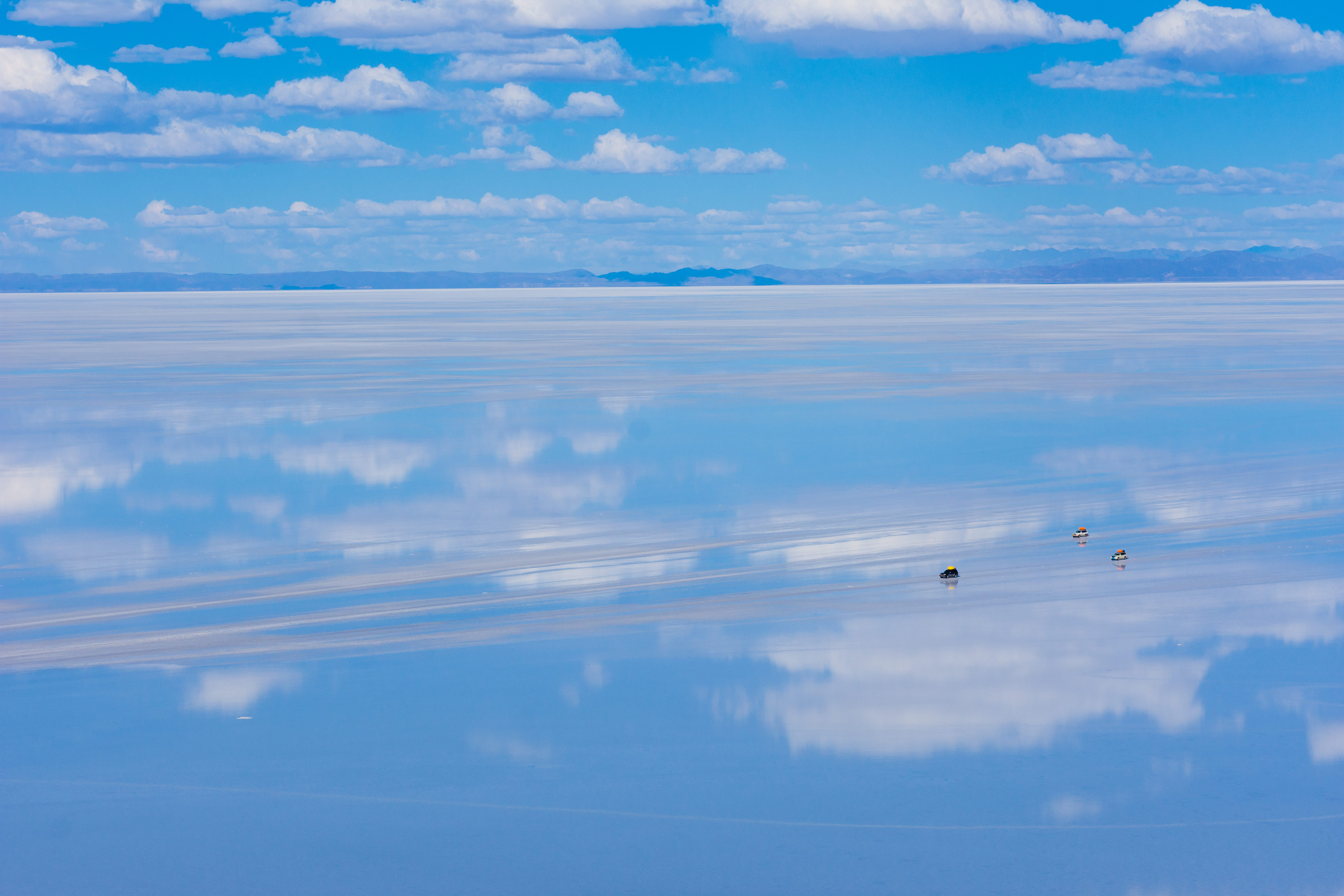 天空の鏡と呼ばれる雨季のウユニ塩湖を横断する車の写真 画像 フリー素材 ぱくたそ