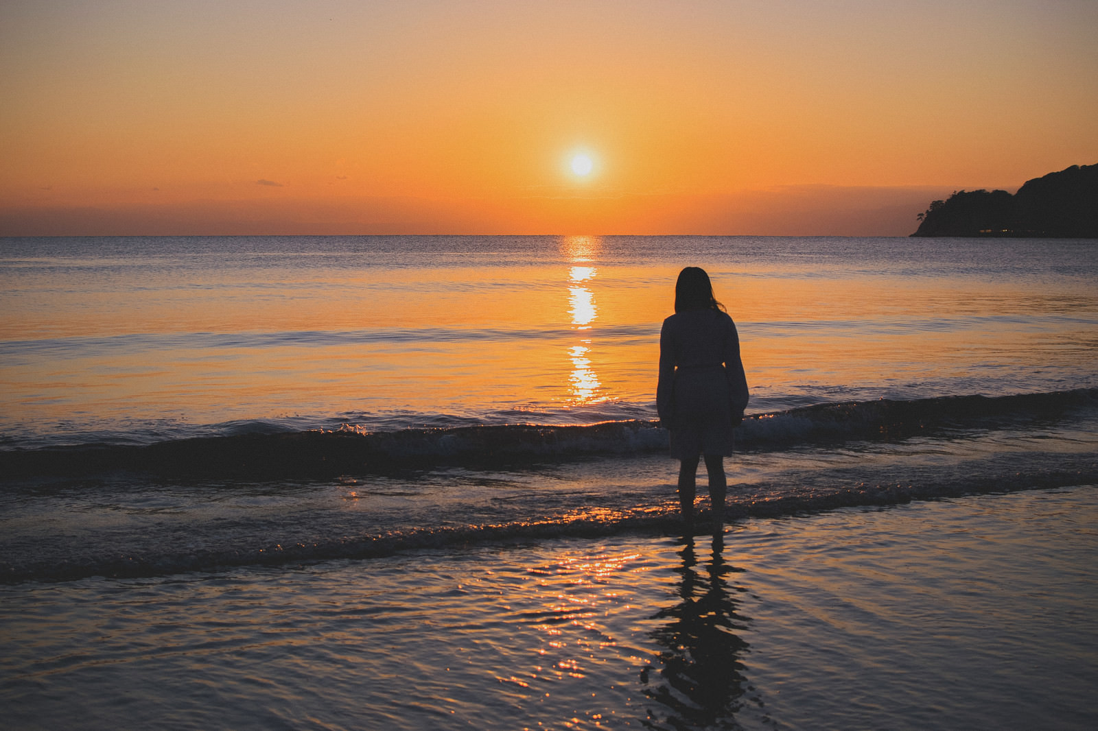 夕日に向かって浜辺に立ちすくむ女性の写真を無料ダウンロード フリー素材 ぱくたそ