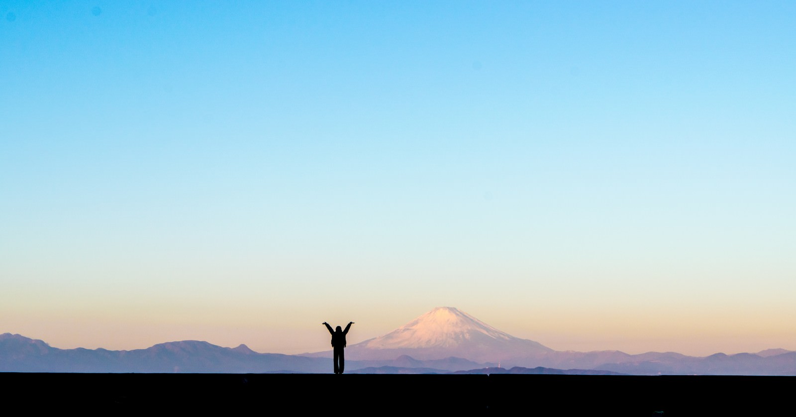 「新年！富士山をバックに両手をあげる女性のシルエット」の写真