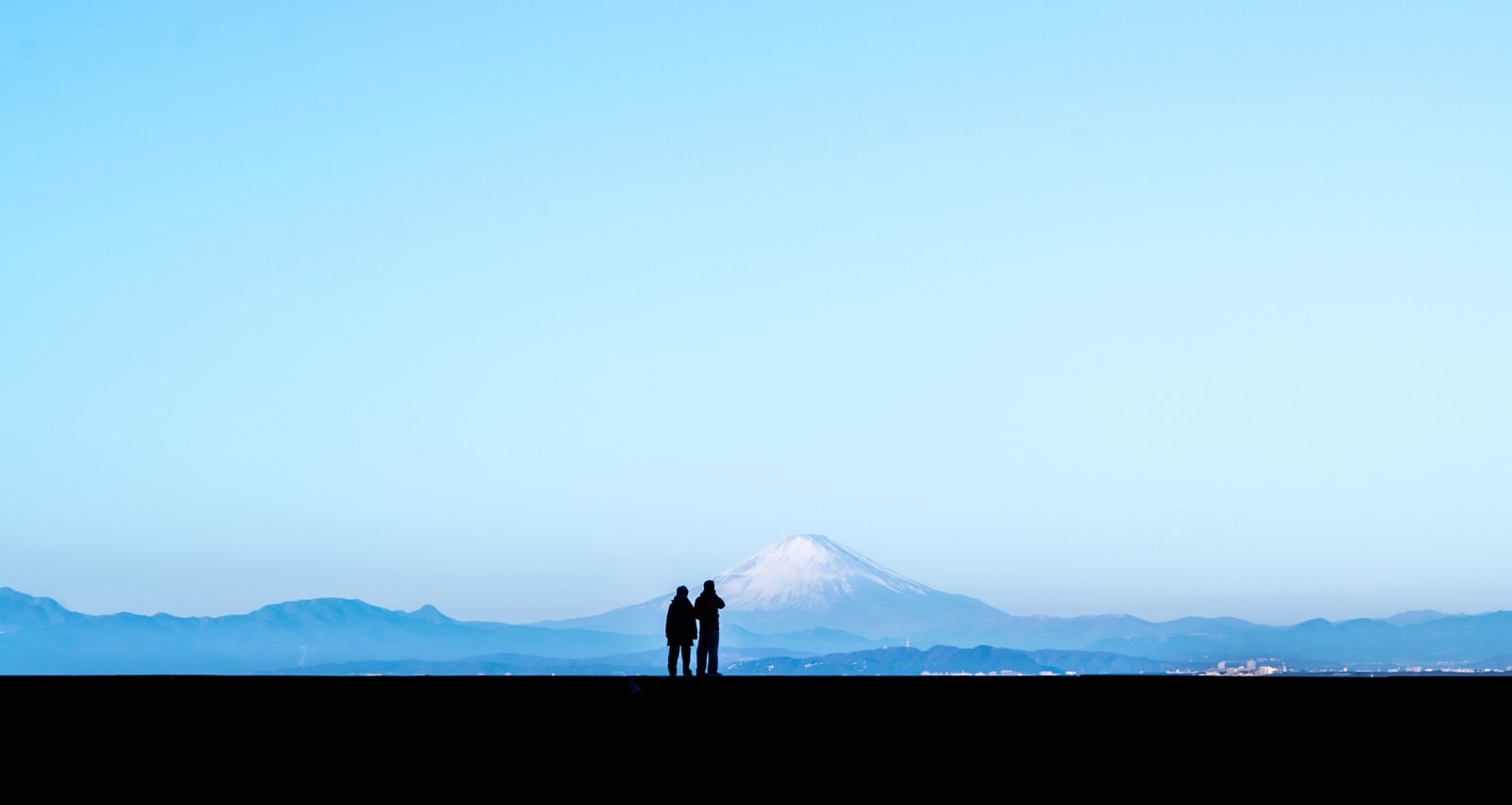 「カップルで快晴の富士山を見ているシルエット」