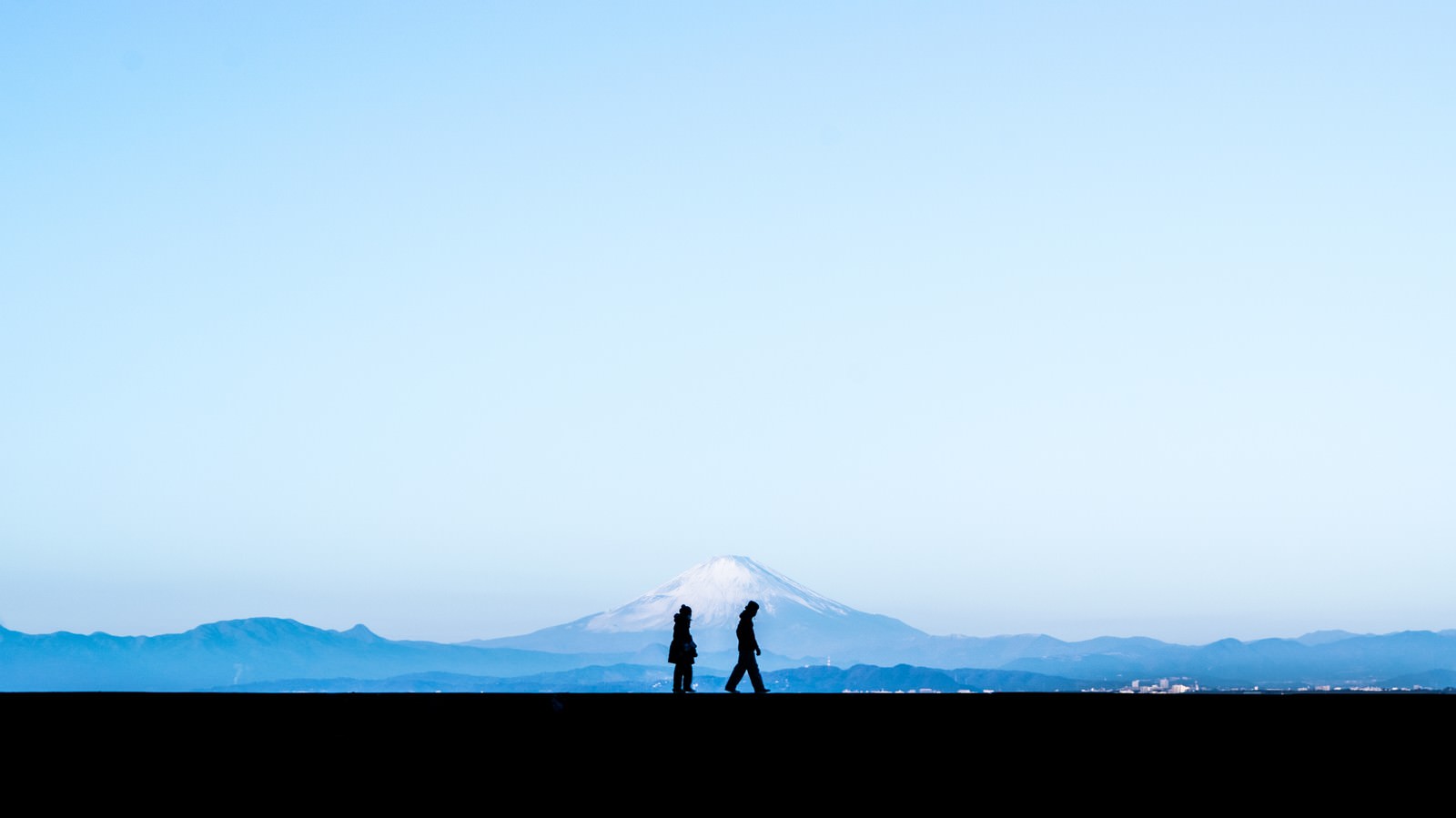 「富士山を見ながら散歩する恋人のシルエット」