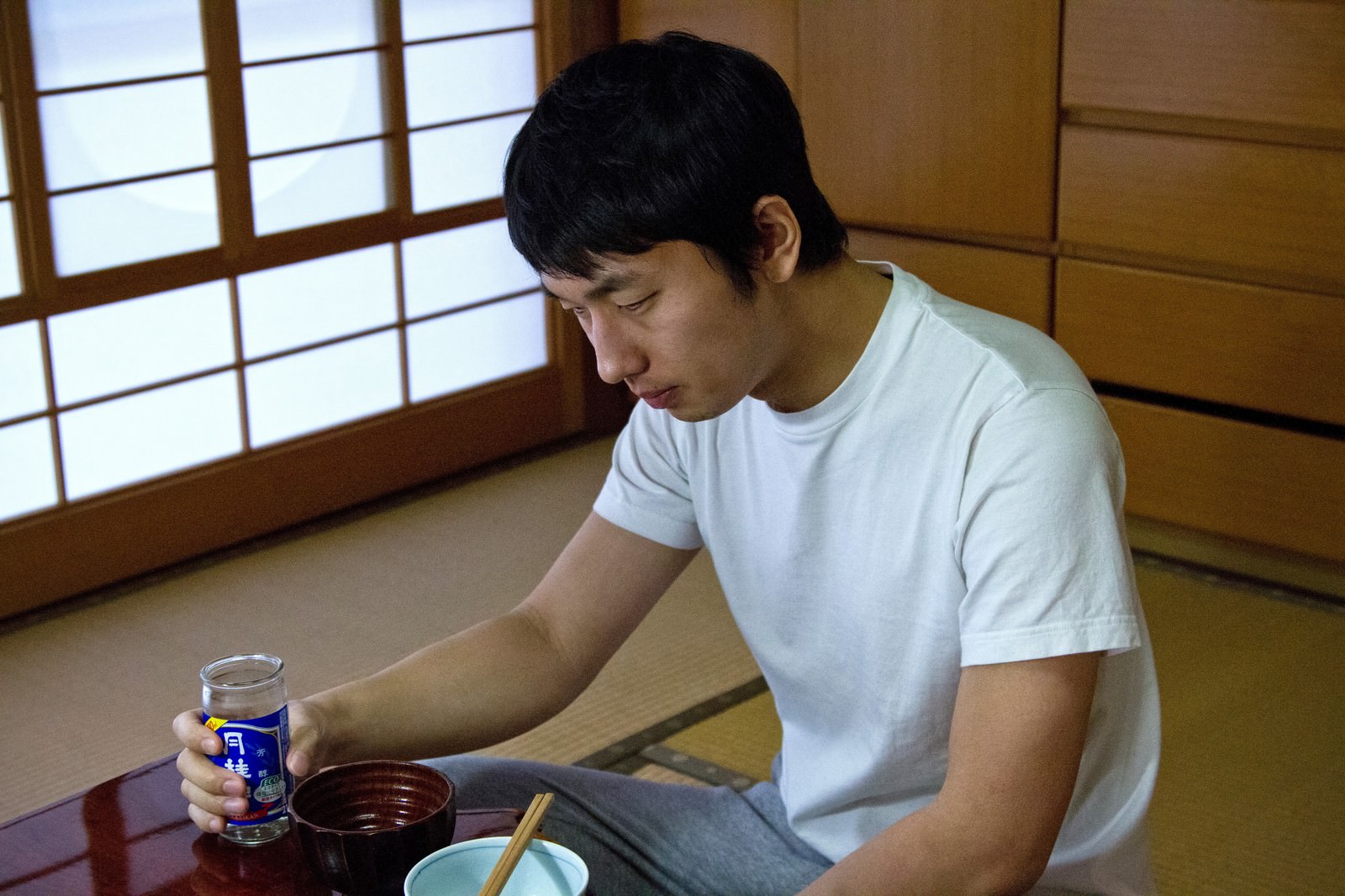 お酒を持ちながら食卓でうなだれる男性の写真 画像 フリー素材 ぱくたそ