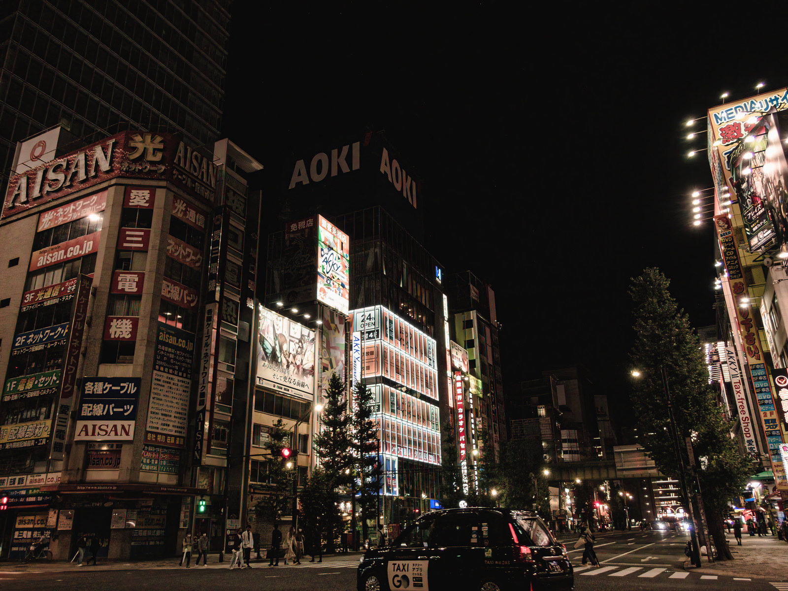 「交差点のタクシーと夜の秋葉原 | フリー素材のぱくたそ」の写真