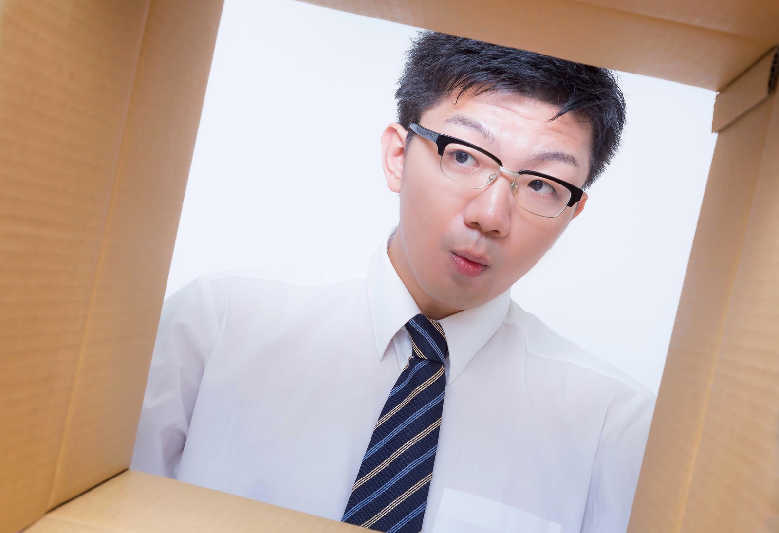 ダンボールを開封して中身を覗くサラリーマンの写真素材 ぱくたそ