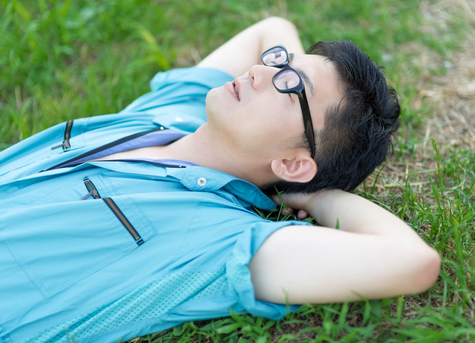 休憩中 芝生で空を眺める青い作業着姿の男性の写真 画像 フリー素材 ぱくたそ