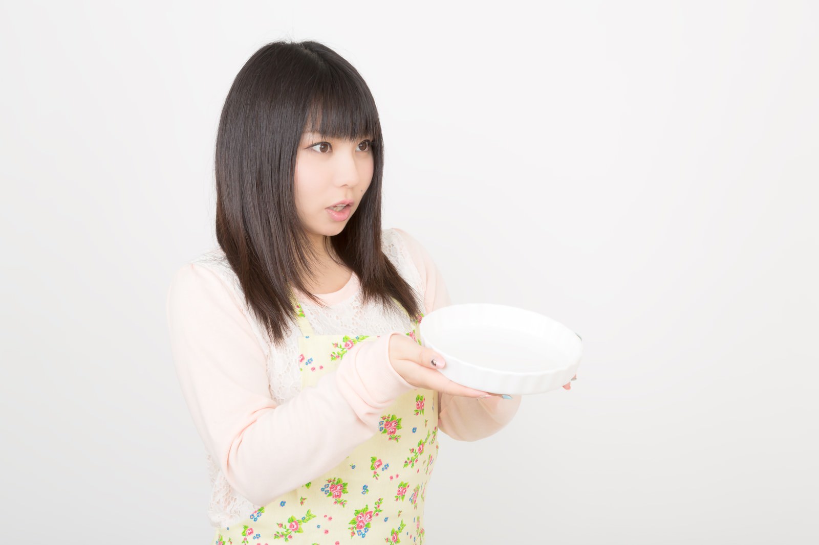 大きなお皿を両手で持ったエプロン姿の女性の写真素材 ぱくたそ