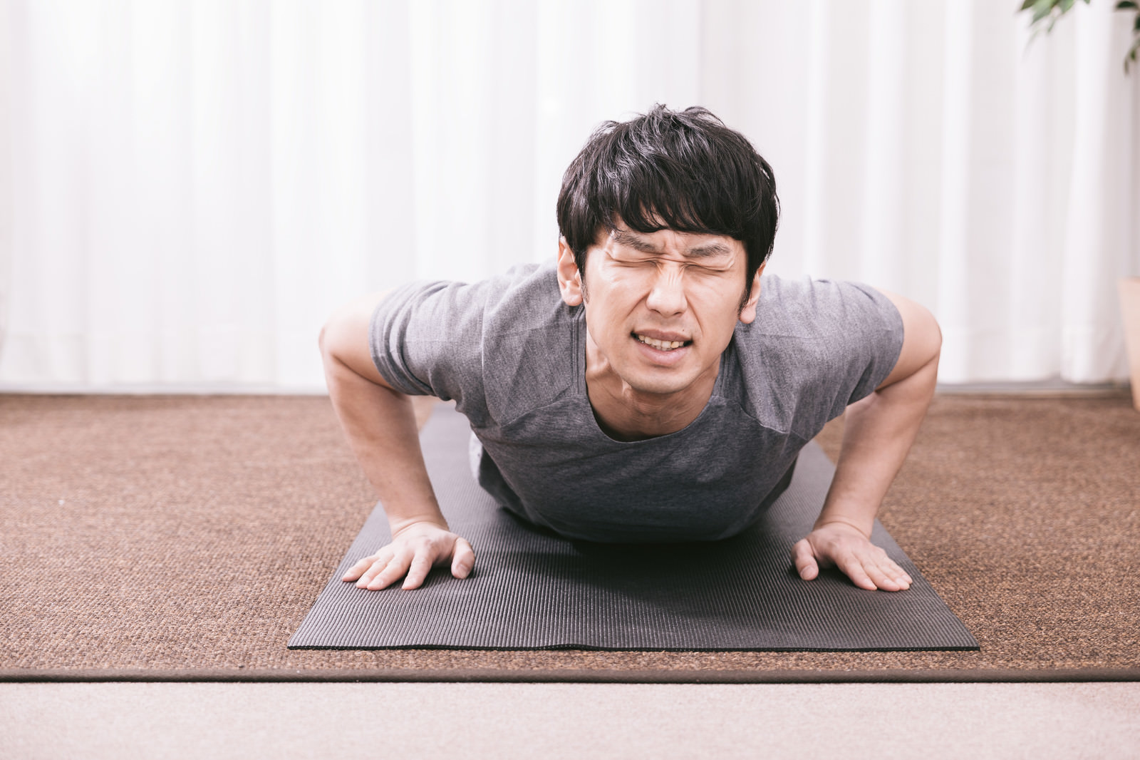 「疲労物質が溜まり苦痛に顔を歪める男性」の写真［モデル：大川竜弥］