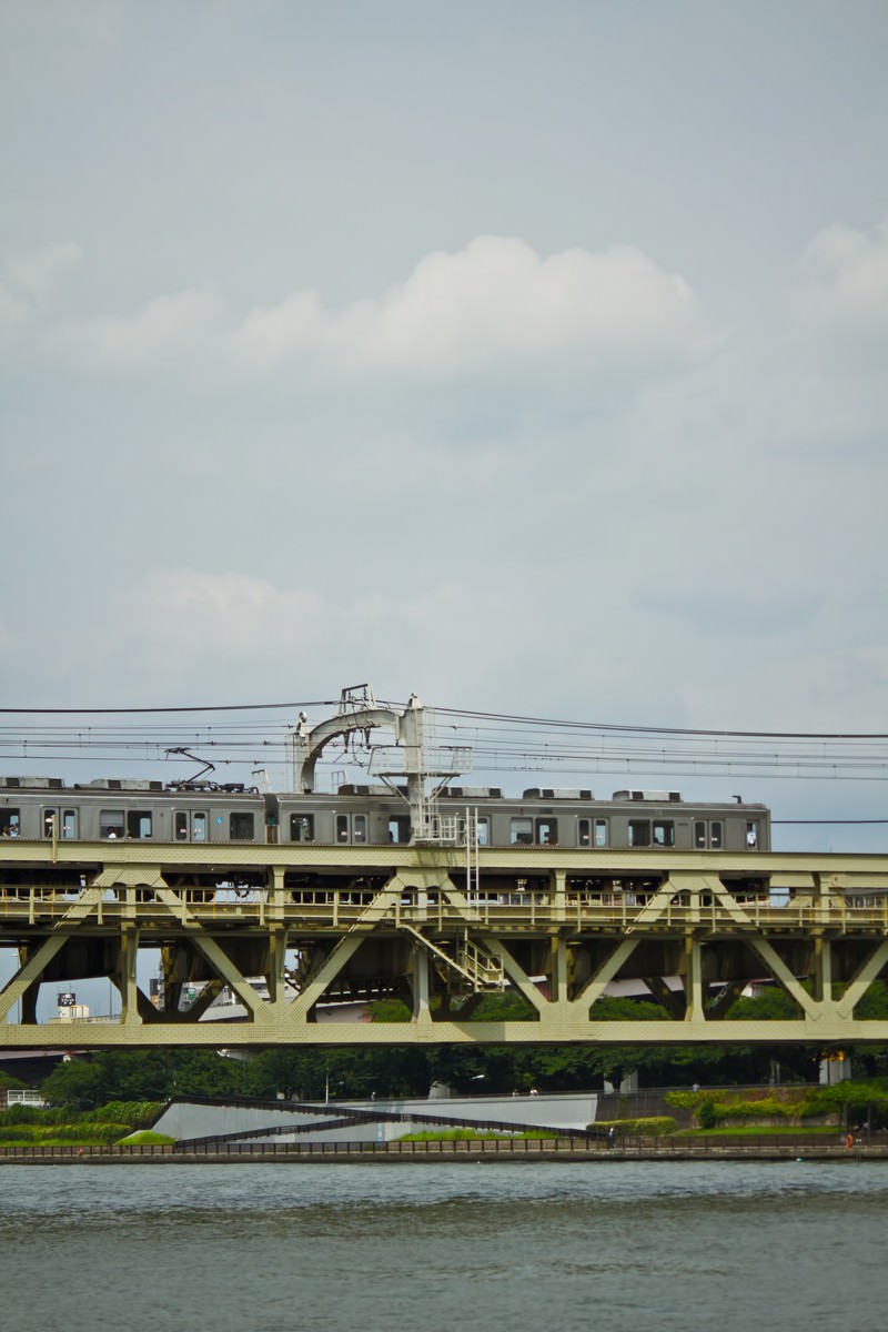 「隅田川を通過する電車 | フリー素材のぱくたそ」の写真