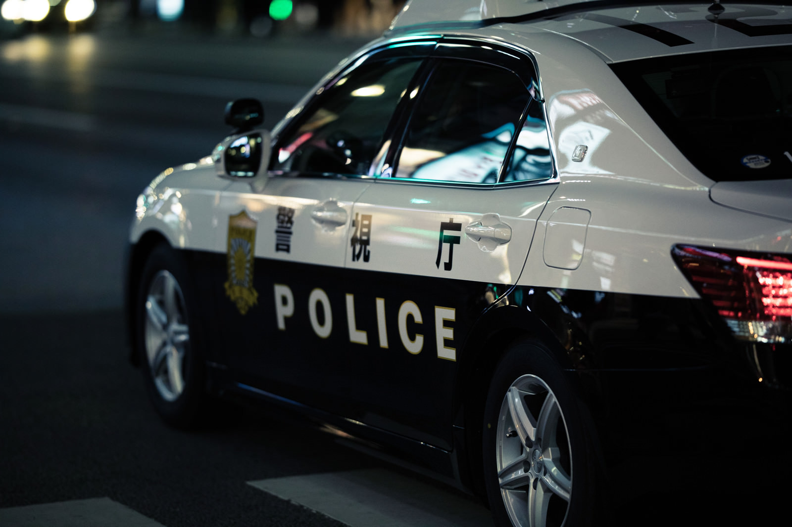 「警察車両に映る夜のネオン」の写真