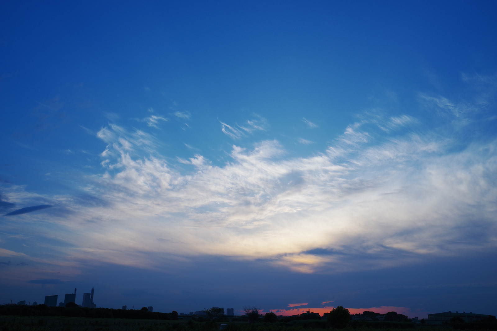「さいたま新都心の向こうへと沈んでいく夕日と雲の青空 | フリー素材のぱくたそ」の写真