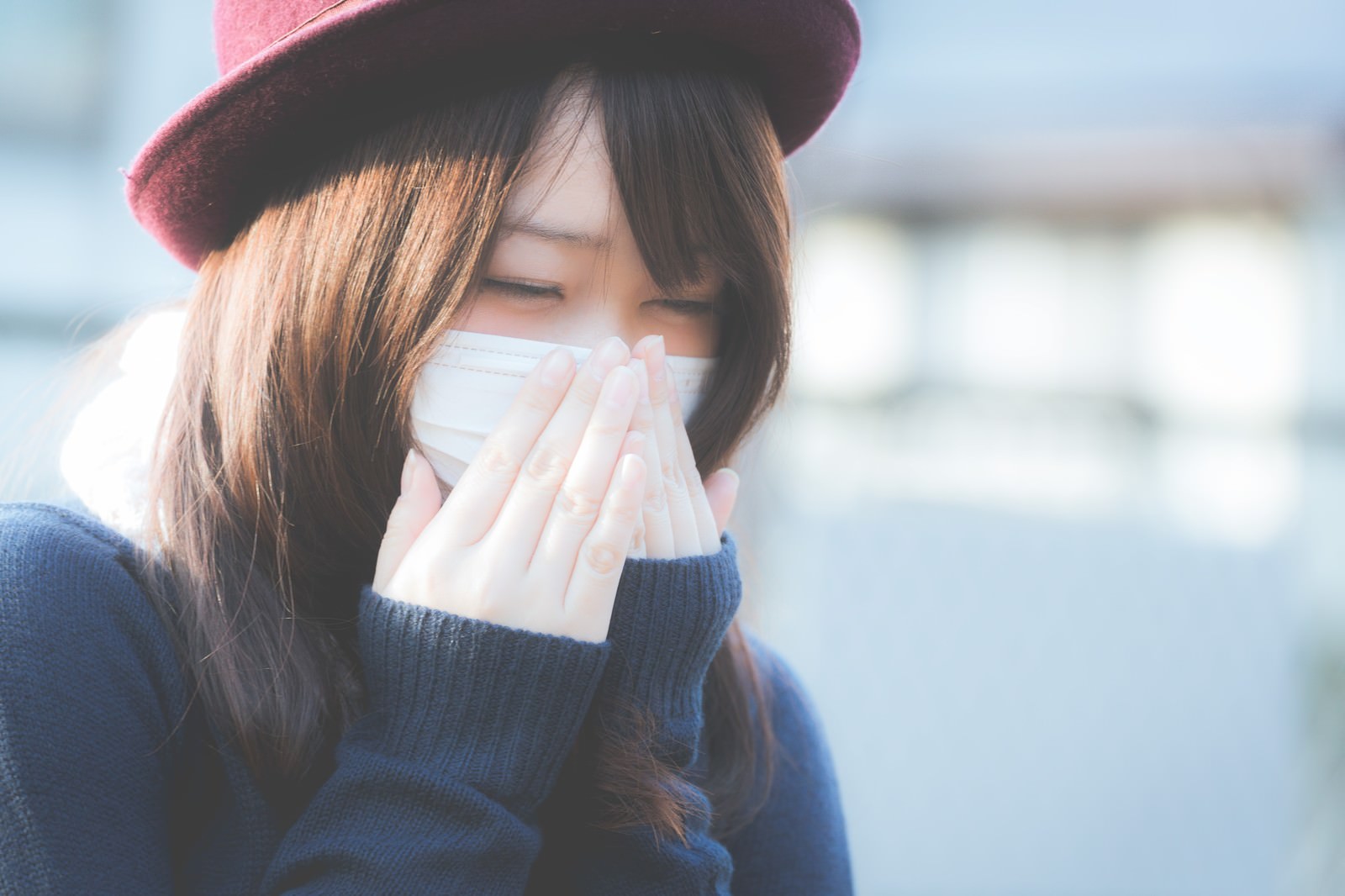 「花粉症でくしゃみが止まらないマスクをした女性」の写真［モデル：茜さや］