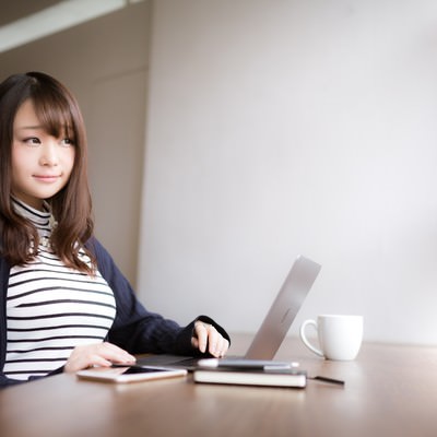 「気分を変えてカフェで作業をするノマド女子」の写真素材