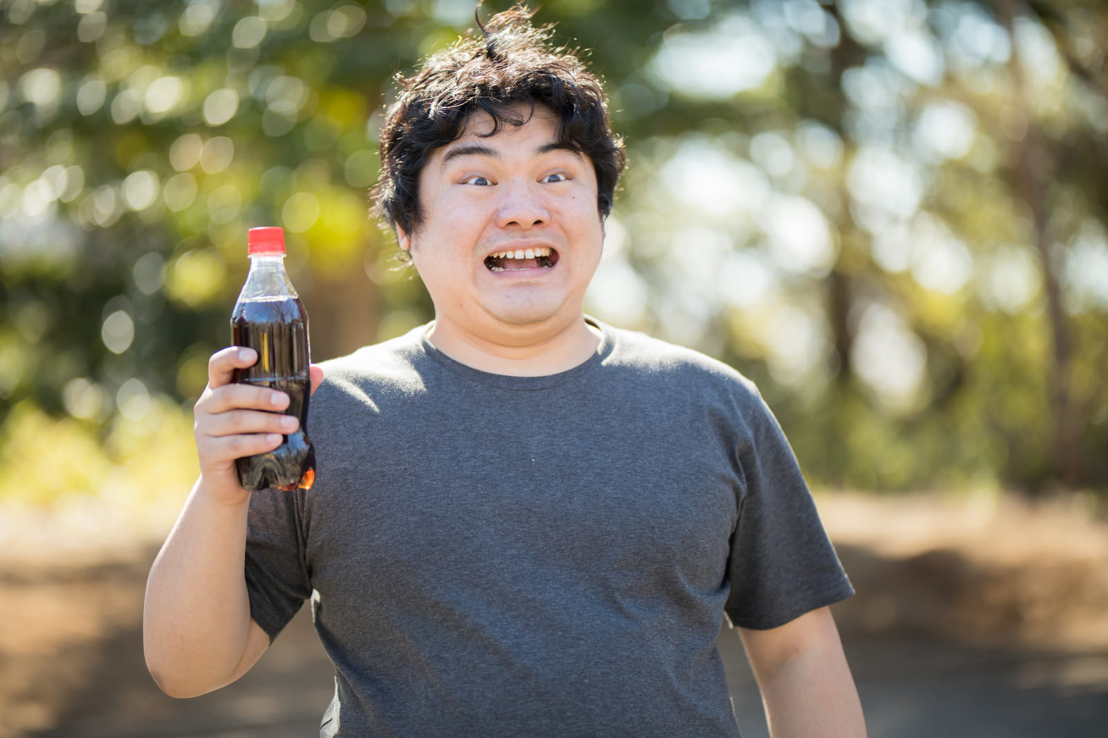 「コーラ片手に不気味な笑みを浮かべる太っちょさん」の写真［モデル：段田隼人］