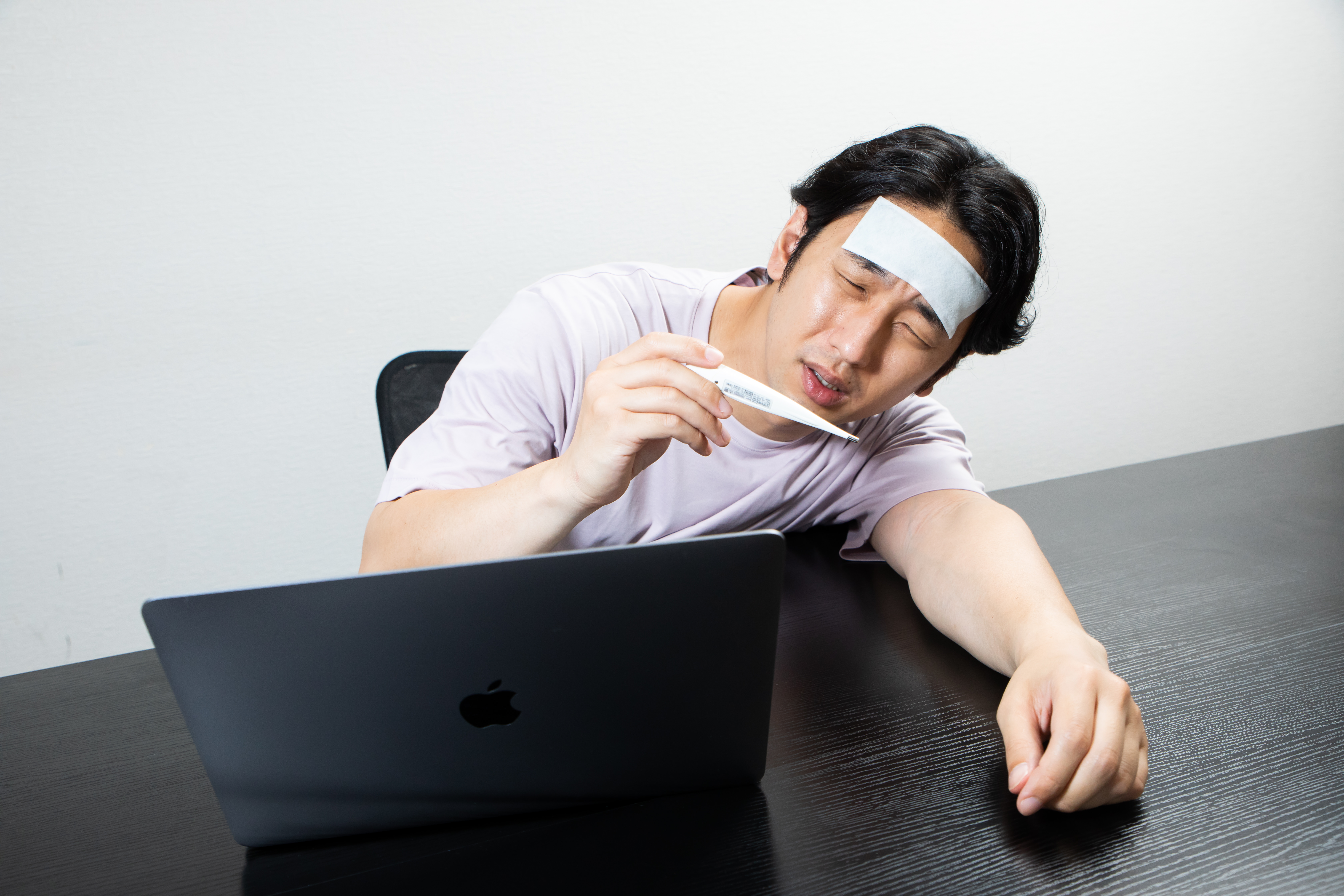 体温計を見て熱のせいだったのかと項垂れる男性の写真素材 ぱくたそ
