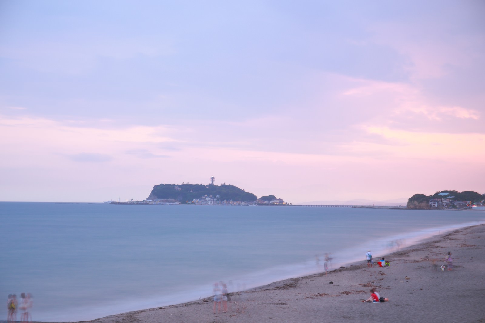 夕焼けの江ノ島と砂浜で楽しむ人々の写真素材 ぱくたそ
