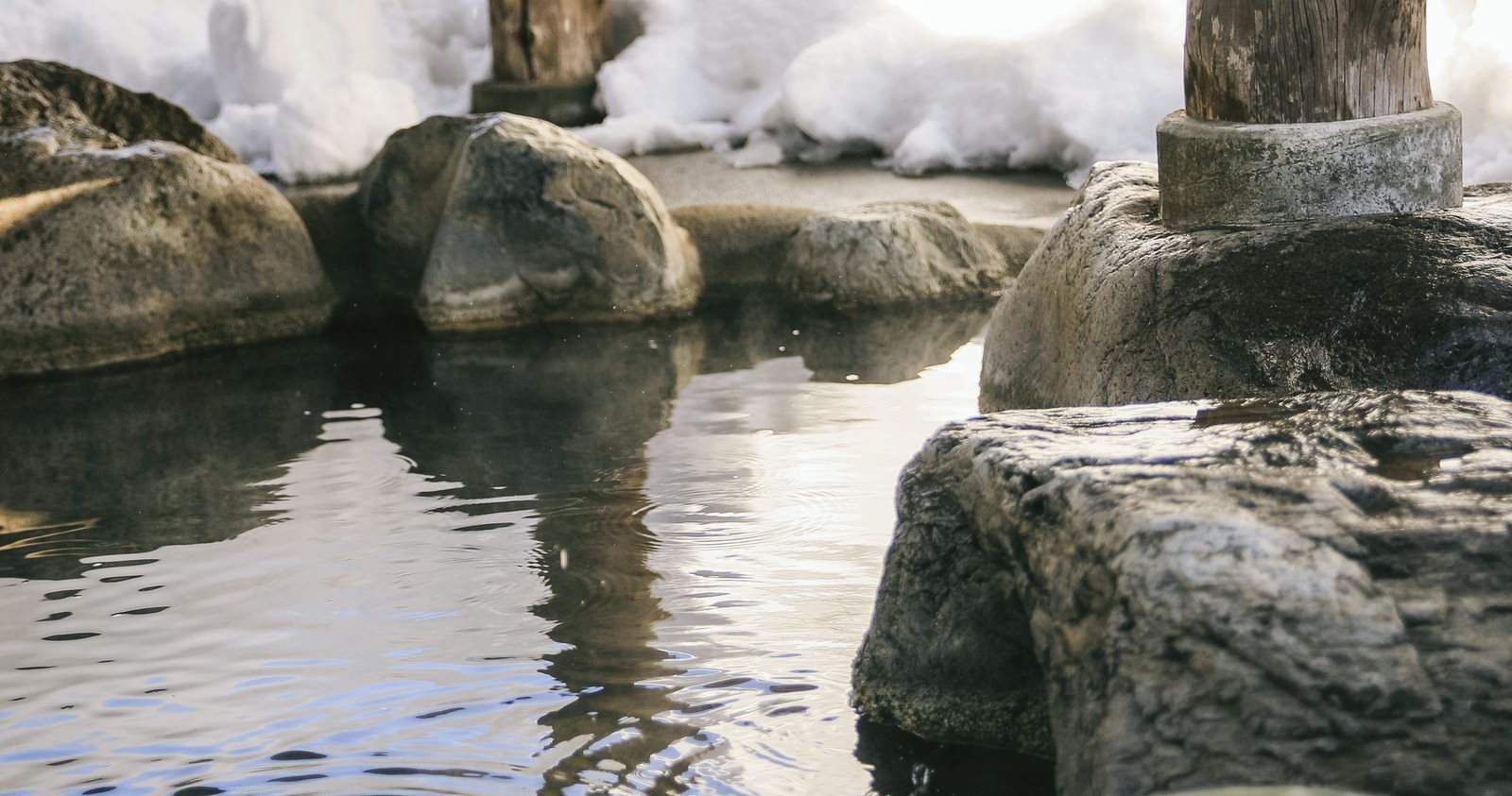 「腰を掛けると滑らかで心地よい岡田旅館の岩露天風呂 | フリー素材のぱくたそ」の写真