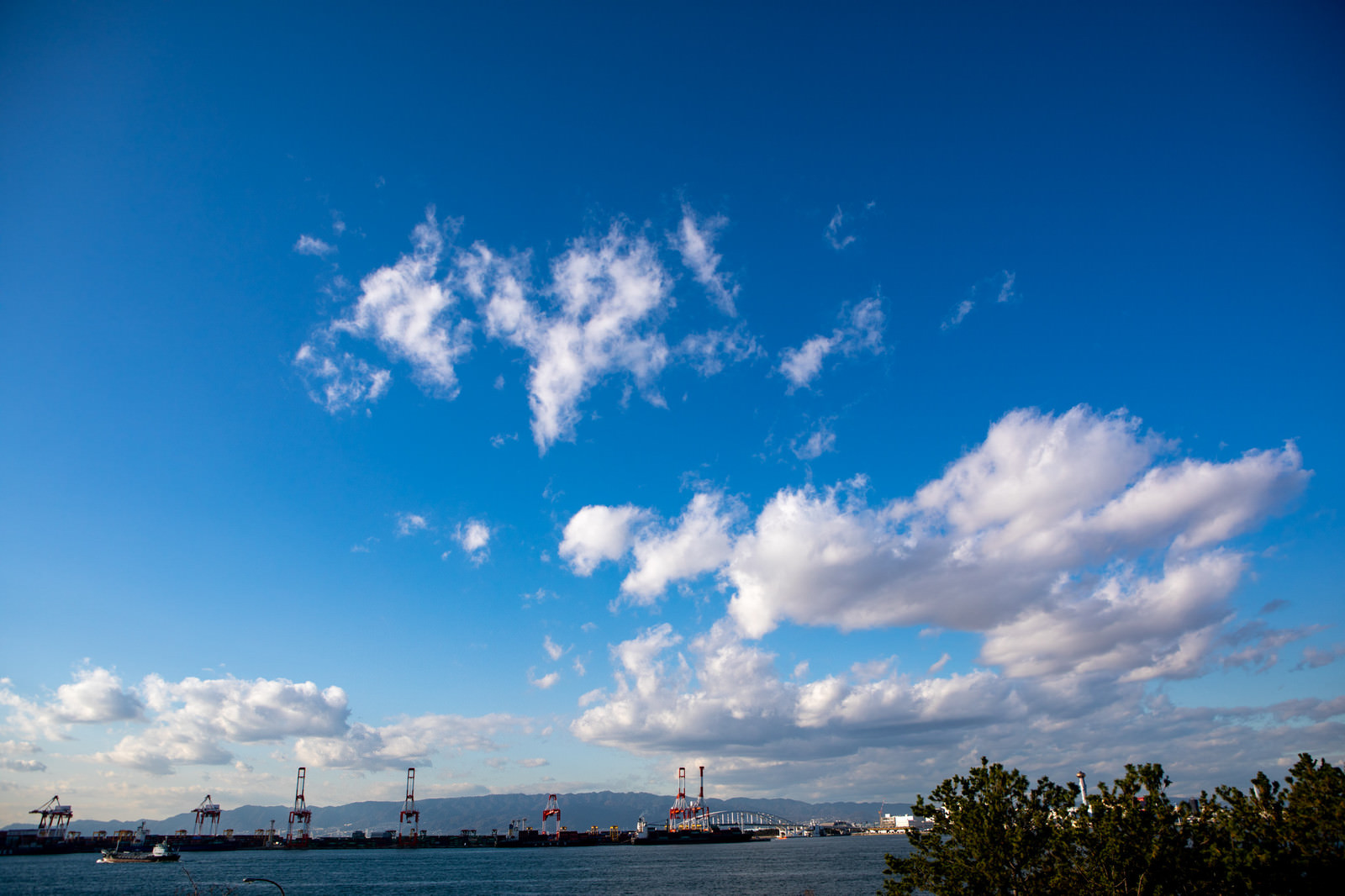 「青空に浮かぶ雲とコンビナート」の写真