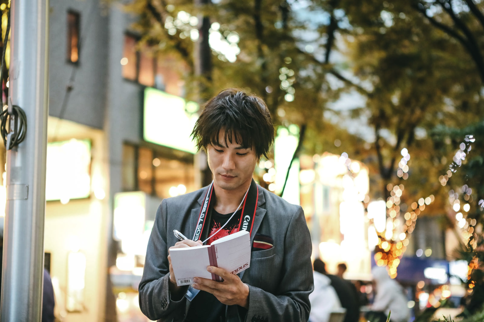 「屋外で取材中にメモを取る男性」の写真［モデル：村田裕章］