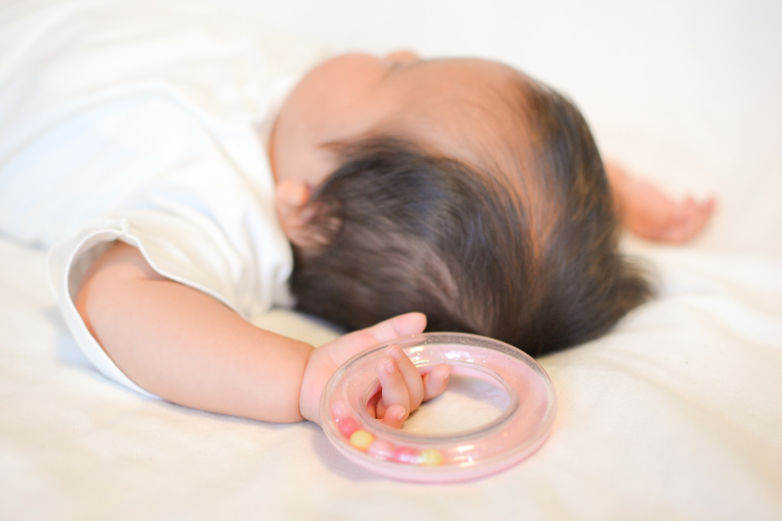 「寝ながら両手をあげる新生児」の写真