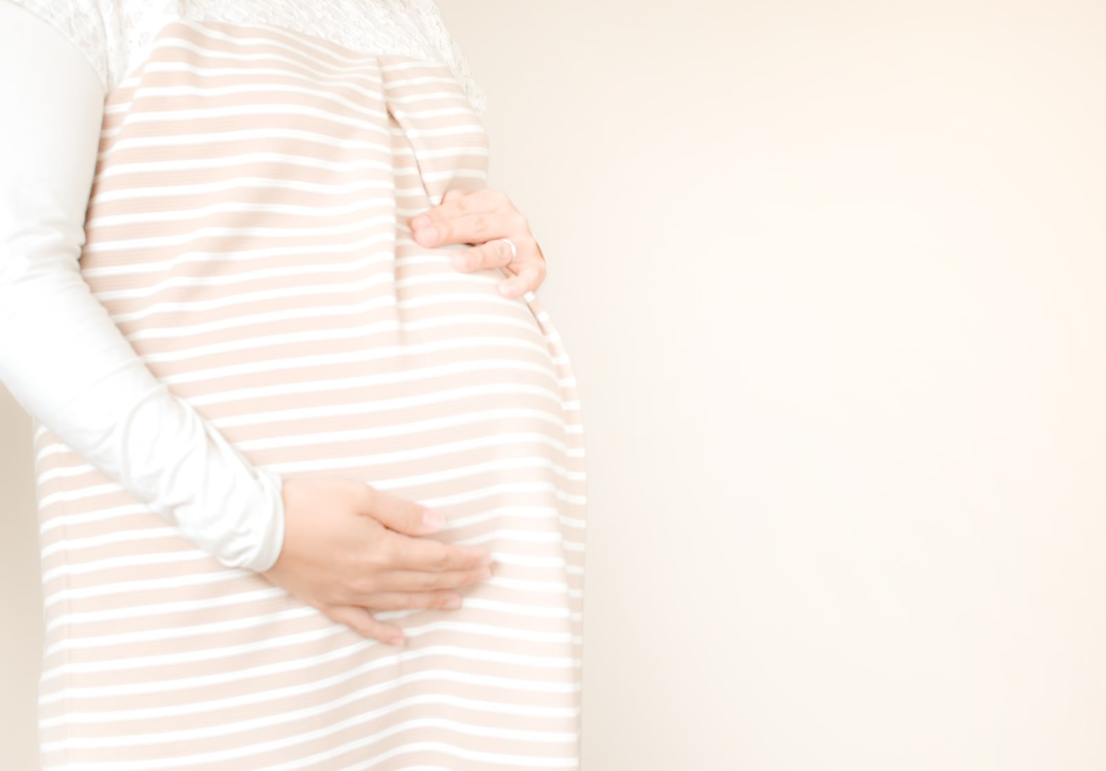 「お腹の胎動を感じる母親 | フリー素材のぱくたそ」の写真